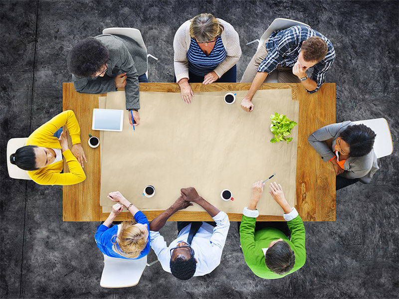 Eight people sitting around a table talking.