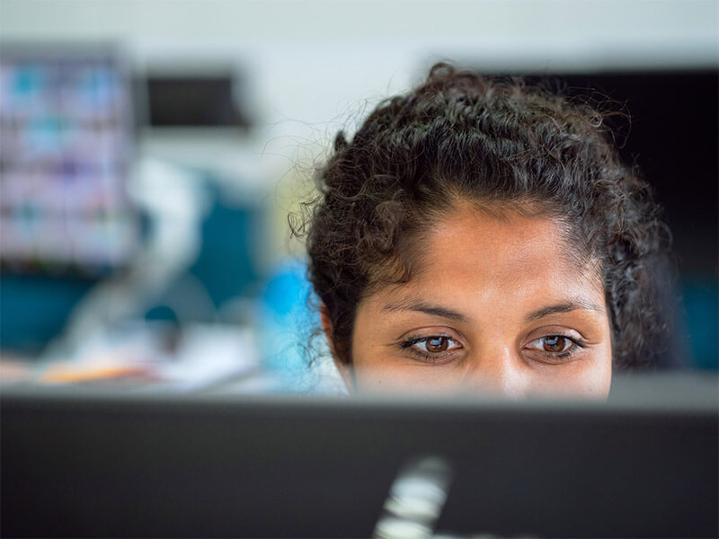 A woman looking at a computer monitor.